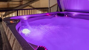 A hot tub with purple lighting, a metal roof, and a view of buildings in the background. - Modern Happy Valley Executive TH with Hot Tub (Beaverdell)