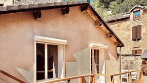 A rustic building with a wooden deck and two windows.