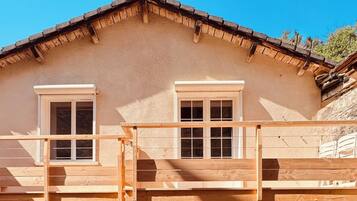 Un chalet rustique doté d’un balcon en bois et de deux fenêtres.