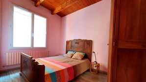 A bedroom with a wooden bed, a radiator, a window, and a door.