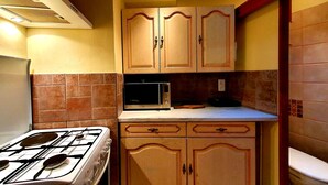 A compact kitchen with a gas stove, microwave, and wooden cabinets.