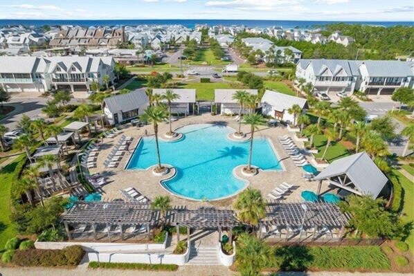 A resort with a central swimming pool, sun loungers, and a view of the surrounding area.