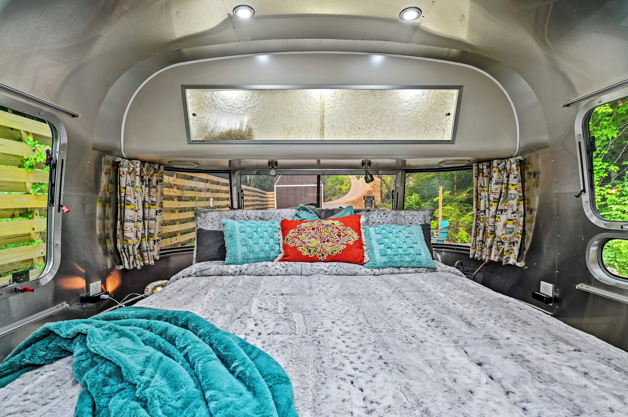 A bed with a patterned blanket, pillows, and a window with curtains.