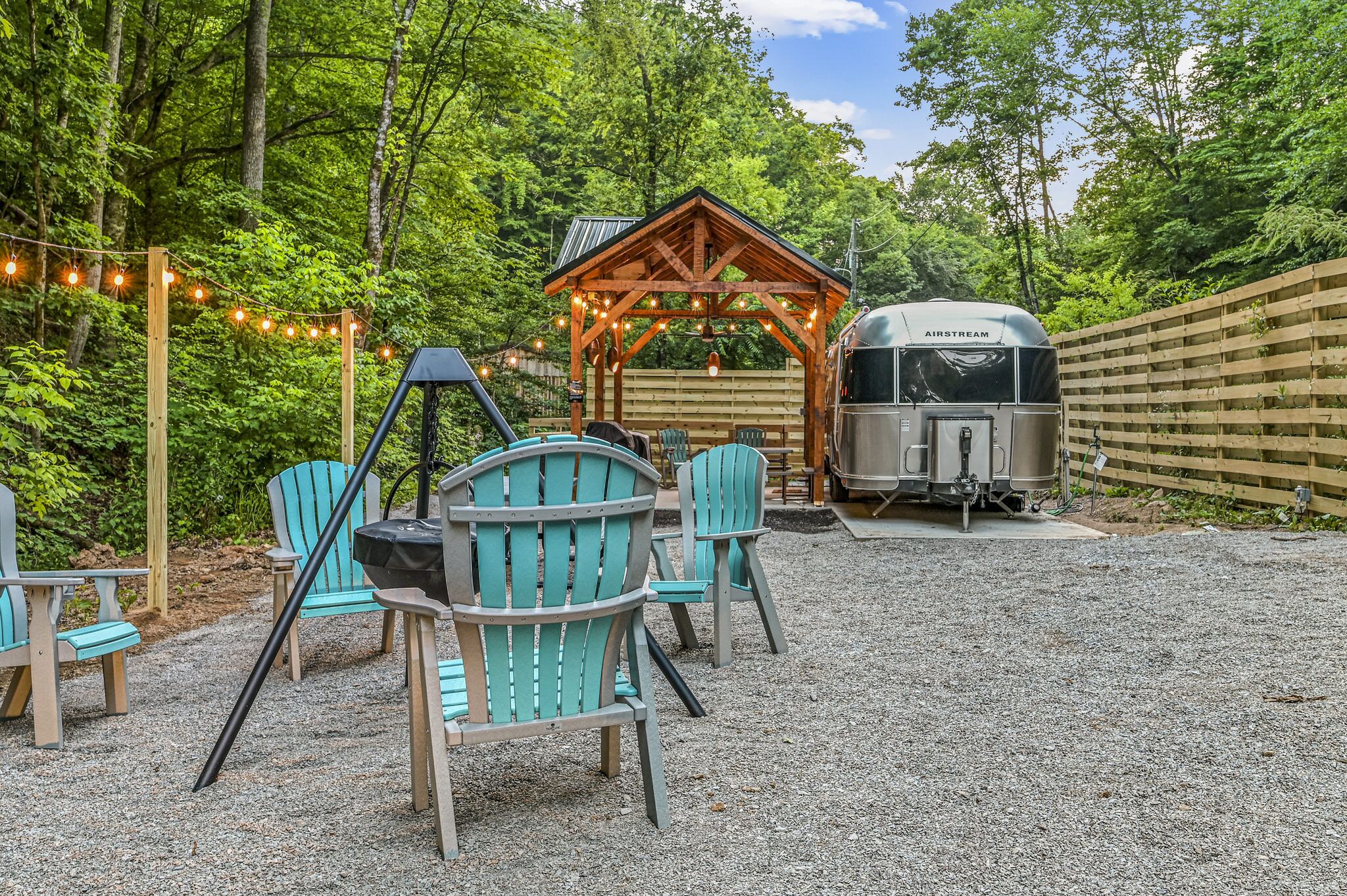 An outdoor seating area with Adirondack chairs, a wooden gazebo, and a covered grill area.
