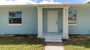 A single-story house with a light blue exterior, a white front door, and a small porch with steps. - Discover Micco charm, just a quick 23-min drive to Wabasso Beach Park (Micco)
