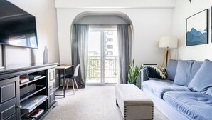 A modern living room with a flat-screen TV, a sofa, a coffee table, and a balcony with a view. - Your Home Base in the Heart of Seattle (Seattle)