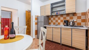 A compact kitchen with a refrigerator, a coffee maker, and a sink.