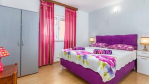 Una camera da letto con un letto, tende, un comodino, una lampada e un armadio.