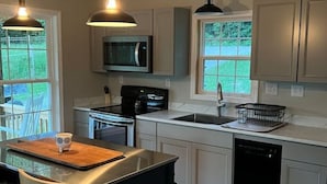 A modern kitchen with a central island, stainless steel appliances, and pendant lighting. - Beautiful Cabin in Red Lick Valley (Irvine)