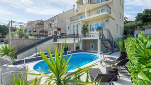 Un immeuble à plusieurs étages doté d’une piscine, d’un espace extérieur aménagé et d’un escalier menant à un balcon.