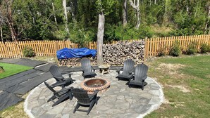Pihalla on kivilaatoitettu terassi, nuotiopaikka ja Adirondack-tyyliset puutarhatuolit.