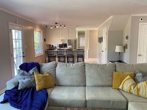 A living room with a grey sectional sofa, a blue blanket, and a yellow pillow. - Masters Rental 5br 3.5ba; Less than 4mi from Augusta National with putting green (Augusta)