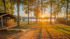 A lakeside cabin with a glass enclosure, a wooden deck, and a picnic area. - Private Lakefront Spread: BigH2O, Smokehouse, Spa, Firepits, Fence, PETS (Eatonton)