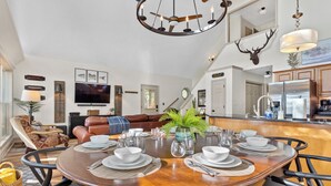 A dining area with a round table set for four, surrounded by chairs. A television is mounted on the wall above the seating area. - Private Lakefront Spread: BigH2O, Smokehouse, Spa, Firepits, Fence, PETS (Eatonton)