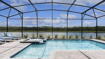 Relax by the serene pool, surrounded by a tranquil lake and lush trees.
