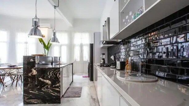 A modern kitchen with a marble island, pendant lighting, and a black backsplash. - Gorgeous Republican. Apt inside old city. (cartagena)