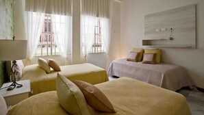 A hotel room with two beds, a desk, and a large window with sheer curtains. - Gorgeous Republican. Apt inside old city. (cartagena)