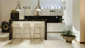 A modern kitchen with a marble island, bar stools, pendant lighting, and a potted plant. - Gorgeous Republican. Apt inside old city. (cartagena)