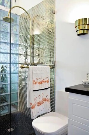 A bathroom with a glass shower enclosure, a toilet, and a sink with a white countertop.