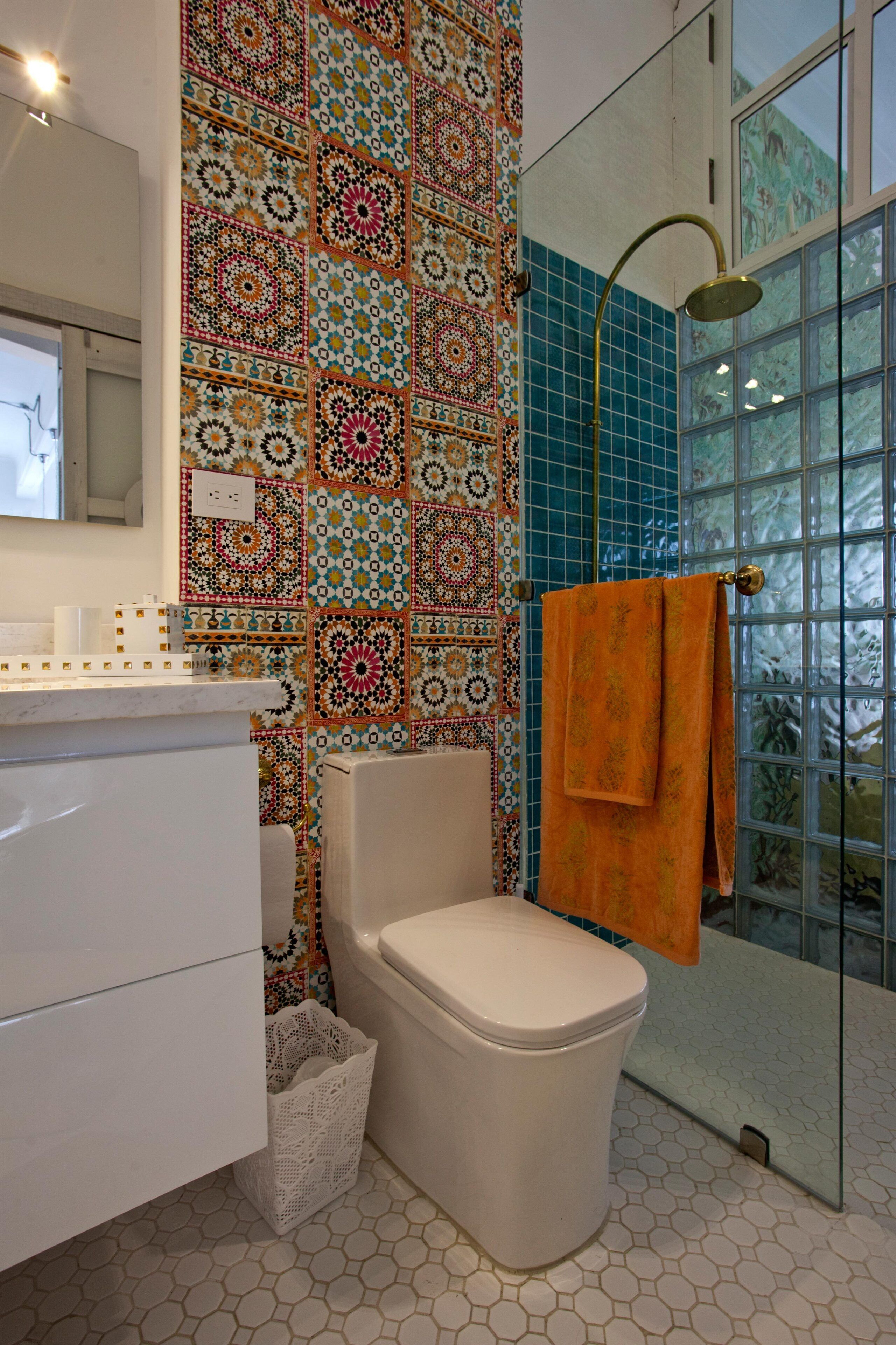 A bathroom with a patterned tile wall, a toilet, a sink, and a shower area.