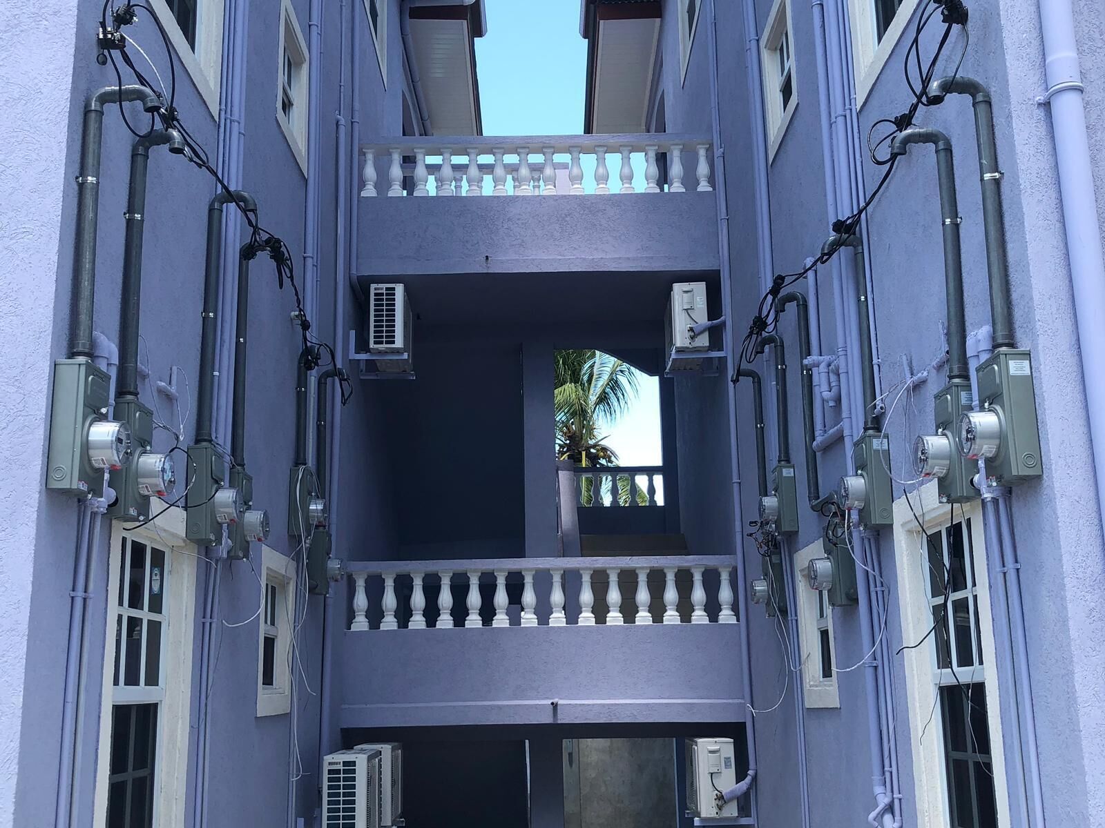A multi-story building with balconies, air conditioning units, and visible electrical wiring.