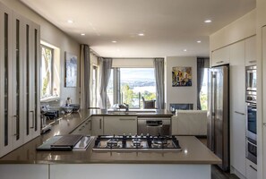 Una cucina moderna con isola centrale, elettrodomestici in acciaio inossidabile e ampie finestre che offrono una vista.