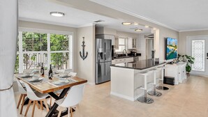 Una cocina moderna con una isla central, electrodomésticos de acero inoxidable y un comedor con vista a zonas verdes.
