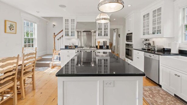 Een moderne keuken met witte kasten, een zwart aanrecht en roestvrijstalen apparatuur.