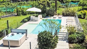 Una piscina con hidromasaje, rodeada por una terraza con asientos y una pérgola.