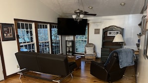 A living room with a sofa, a chair, a TV, and a ceiling fan. - Derby Time Riverside Cabin (Derby)