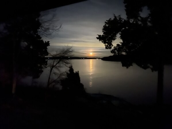 A nighttime view of a calm lake with a sunset, surrounded by trees and a distant bridge. - Derby Time Riverside Cabin (Derby)