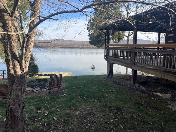 A lakeside park with a wooden deck, a bench, and a gazebo.