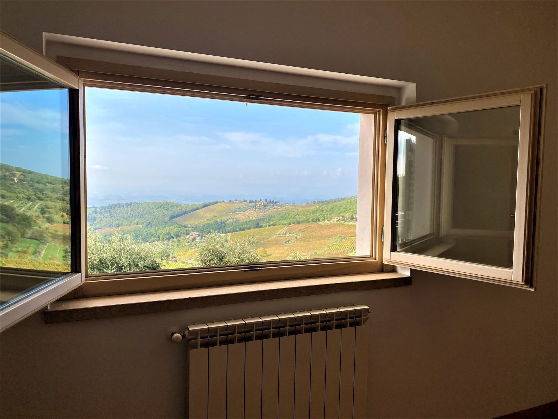 A room with a large window overlooking a hilly landscape.