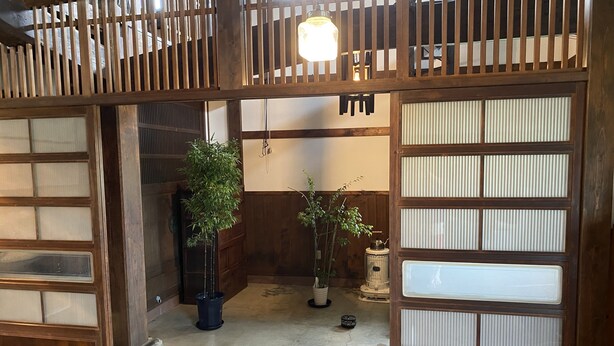 Ein traditionelles japanisches Interieur mit Holz-Schiebetüren, einer Bambuspflanze und einem kleinen Tisch mit Teekanne.