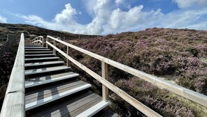 A wooden staircase leading up a hill with a clear sky above.
