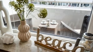 A kitchen counter with a decorative sign spelling "beach," a white vase with flowers, and a wicker basket.