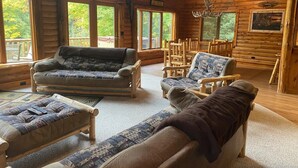 A cozy log cabin interior with a sofa, armchairs, and a fireplace. - Seney Cabin with hot tub (Germfask)