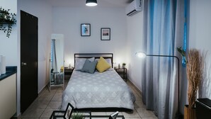 Een moderne slaapkamer met een bed, nachtkastjes, een hanglamp en een raam met gordijnen.