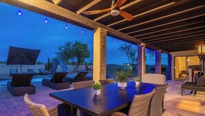 An outdoor patio area with a dining table, chairs, and a ceiling fan. - 6 bd Desert Oasis w/ Pool, Slide, Pickleball+More! (Scottsdale)