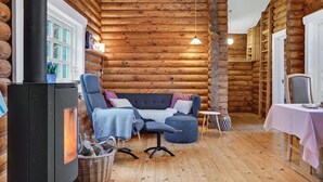 A cozy log cabin interior with a fireplace, a sofa, and a dining table. - 2 bedroom cozy home in Mariager (Mariager)