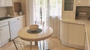 A modern kitchen with white cabinetry, a dishwasher, a sink, and a round dining table with a bowl. - Pent-House, 3 Bedroom, Sleeps 6, Parking (Marbella)