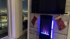 Una sala de estar moderna con chimenea, un televisor de pantalla plana montado encima y dos calcetines decorativos colgados en la pared.