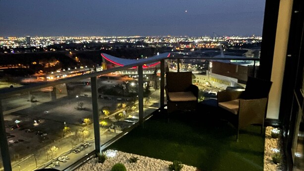 Un balcón con vista a un paisaje urbano al atardecer.
