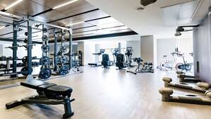 Un gimnasio moderno con diversos equipos de ejercicio, incluyendo máquinas de pesas, cintas de correr y pesas sueltas.