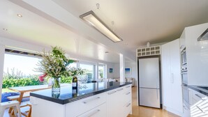 A modern kitchen with white cabinetry, a black countertop, and a built-in oven. - Palm Ridge - near Onetangi & Palm Beach (Waiheke Island)