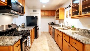 A kitchen with wooden cabinets, a stainless steel stove, a black refrigerator, and granite countertops. - Comfortable Spacious Newly Renovated 3br-2ba House (Tucson)