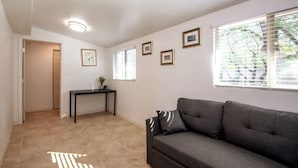 A living room with a sofa, a small table, and framed pictures on the wall. - Comfortable Spacious Newly Renovated 3br-2ba House (Tucson)