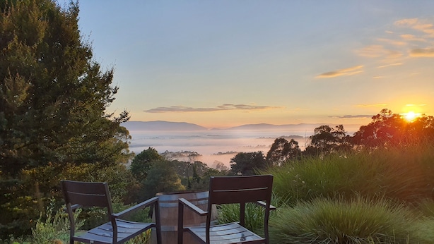 Een tafel met twee stoelen met uitzicht op een schilderachtig valleibekzicht bij zonsopgang of zonsondergang.