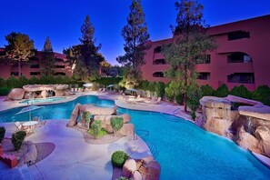 Un hôtel doté d’une grande piscine extérieure, entouré de formations rocheuses et d’arbres.