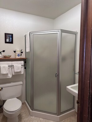 A bathroom with a toilet, a shower enclosure, a sink, and a towel rack with towels.